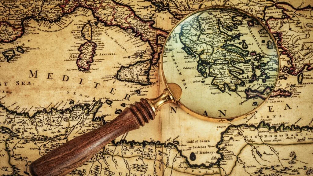 Magnifying glass held over an antique map of the Mediterranean Sea