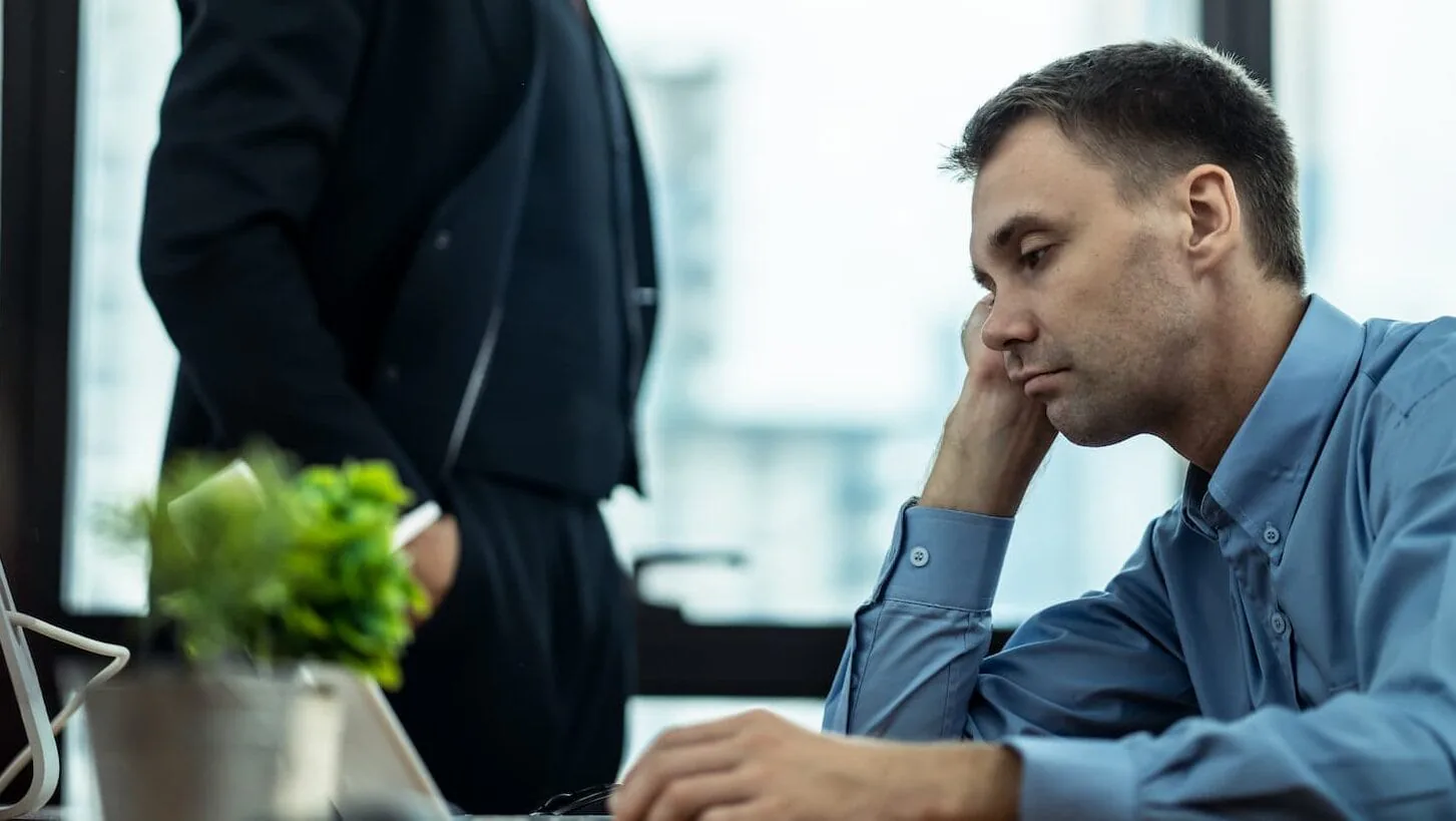 Bored employee in a blue shirt resting his head on his hand at his desk