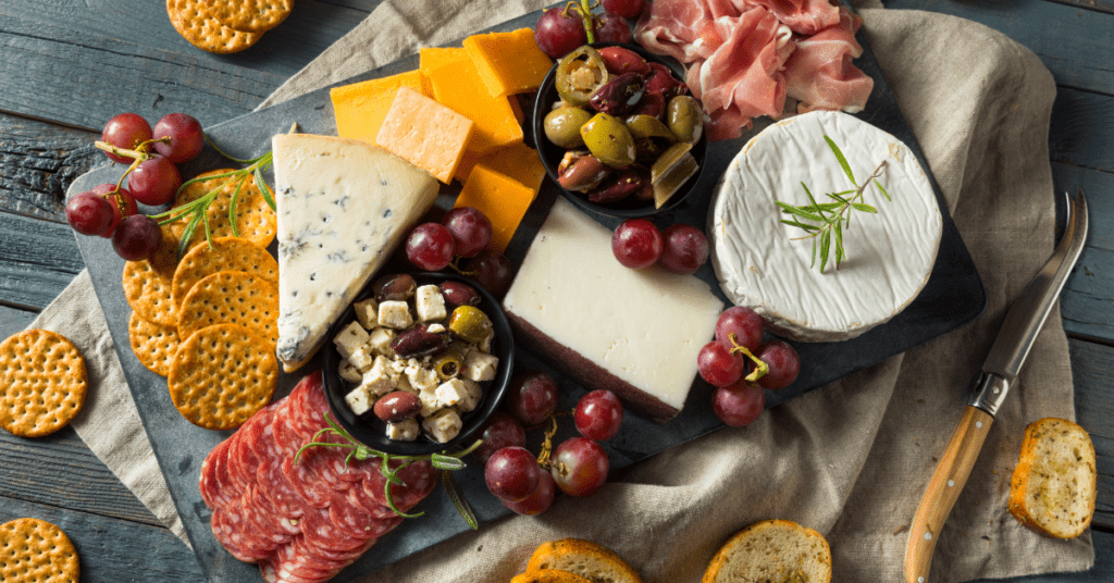 Charcuterie board with brie, cheddar, blue cheese, salami, prosciutto, olives, grapes and crackers