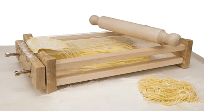Wooden chitarra pasta cutter strung with wires, a rolling pin and a nest of cut spaghetti