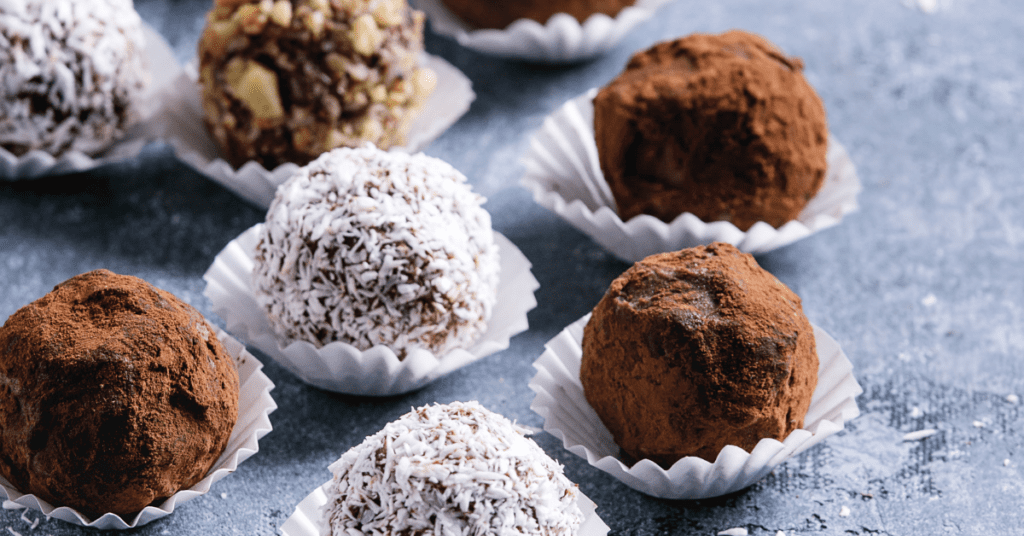 Chocolate truffles rolled in cocoa powder, shredded coconut and chopped nuts in white paper cups