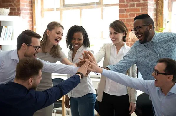 Smiling colleagues stacking their hands together in a huddle in an office