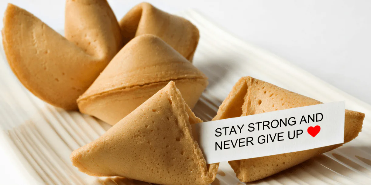 Fortune cookies on a white plate with a slip reading Stay strong and never give up
