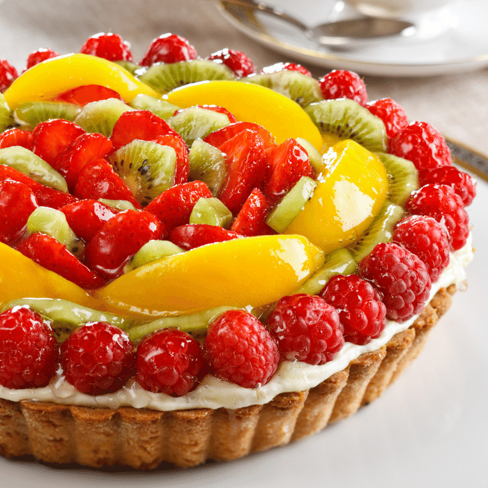 Fresh fruit tart topped with strawberries, raspberries, kiwi and mango over cream in a pastry shell