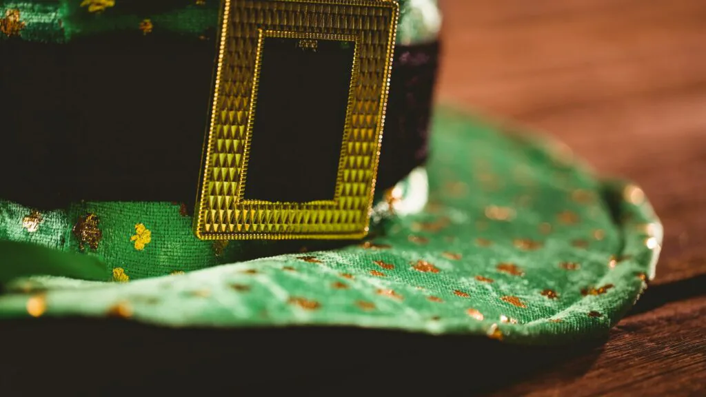 Close-up of a green St. Patrick’s Day hat with a gold buckle on a wooden table