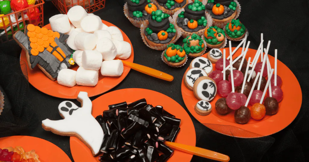 Halloween party treats including a ghost cookie, skull cake pops, marshmallow sticks and cupcakes