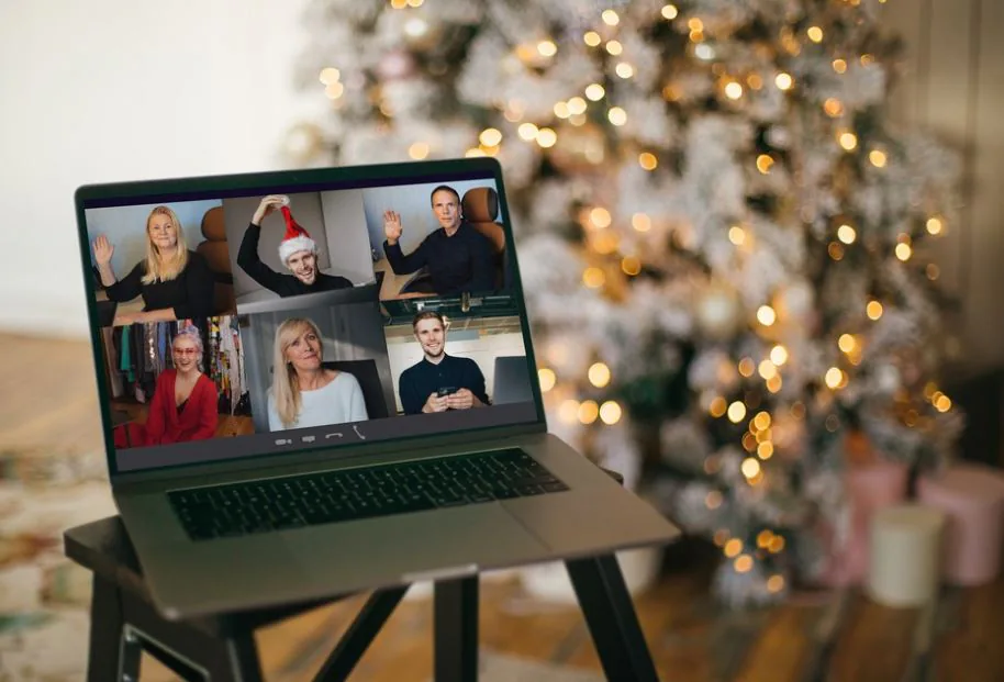 Laptop showing a six-person holiday video call in front of a lit Christmas tree