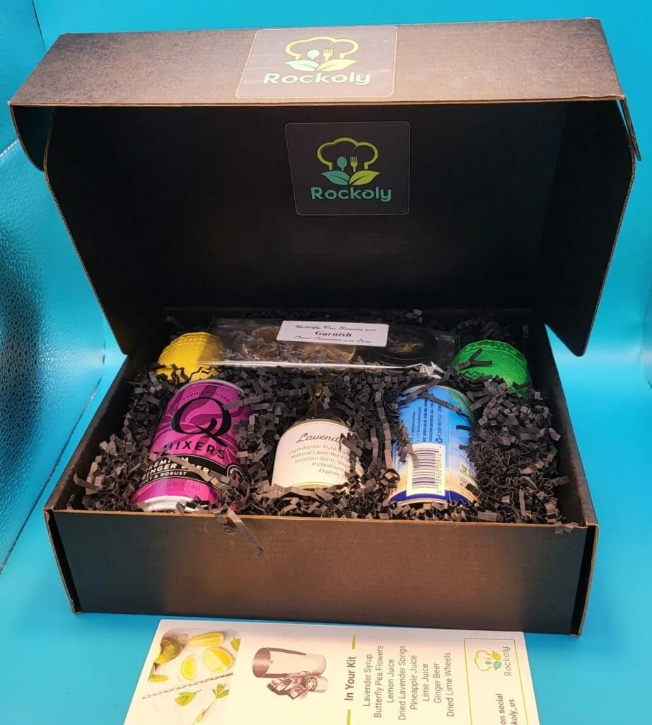 Open Rockoly happy hour kit box holding mixers, a lavender jar, garnishes and a recipe card