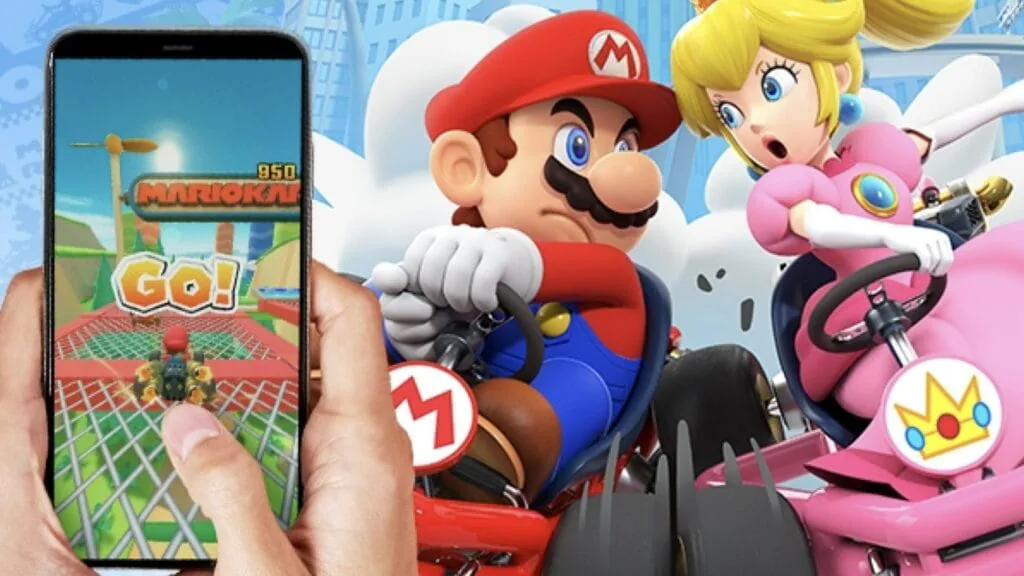 Hand holding a phone running Mario Kart Tour, with Mario and Princess Peach racing beside it