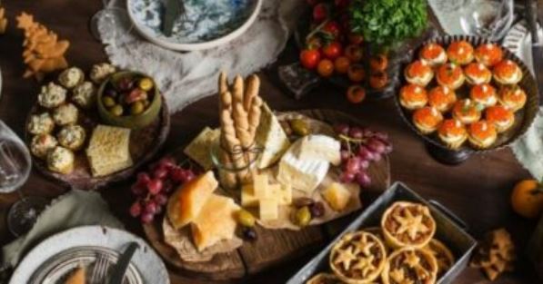 Party spread with a cheese board, breadsticks, grapes, olives, tomato bites and mini tarts