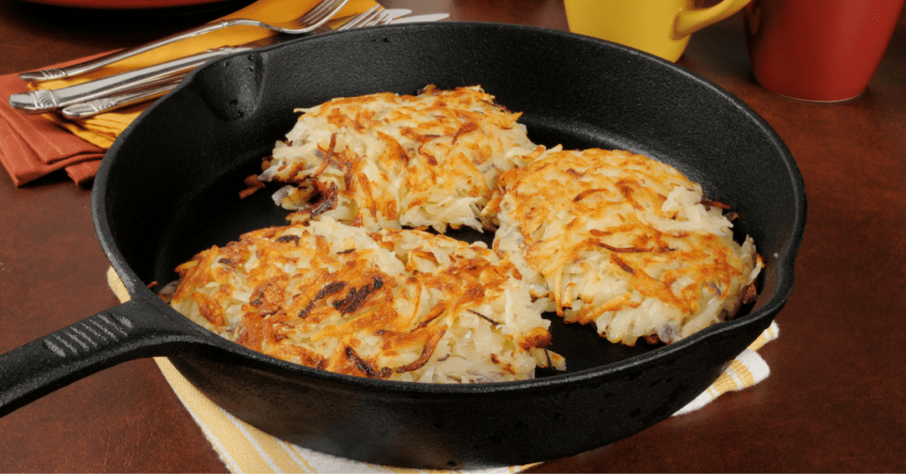 Three crispy golden potato latkes in a cast iron skillet