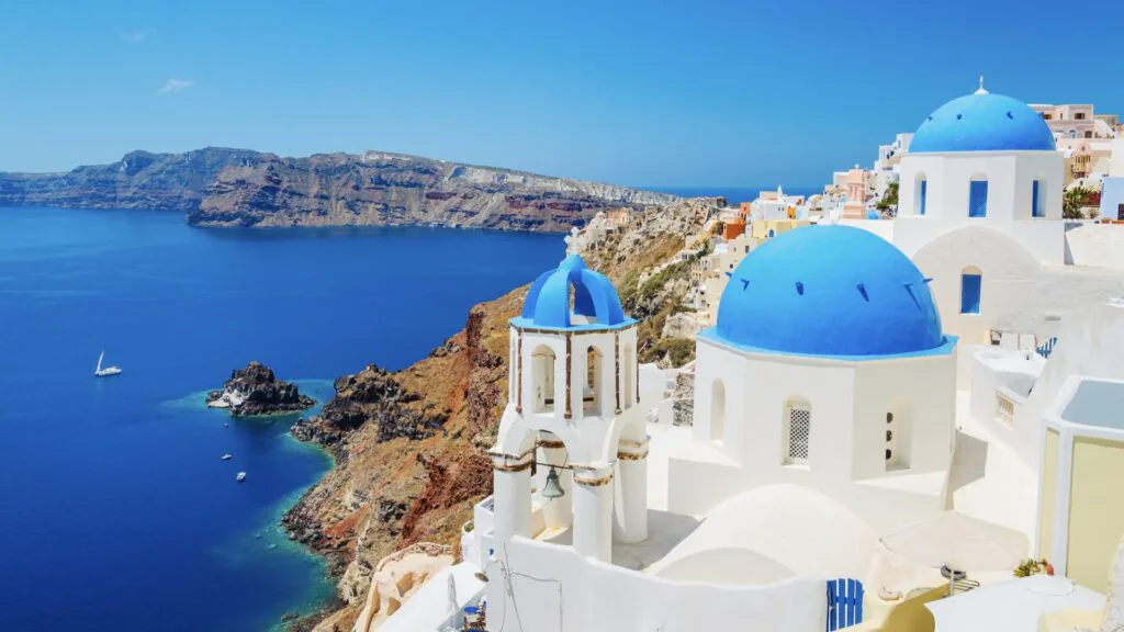 Blue-domed white churches on the Santorini cliffside above the deep blue caldera