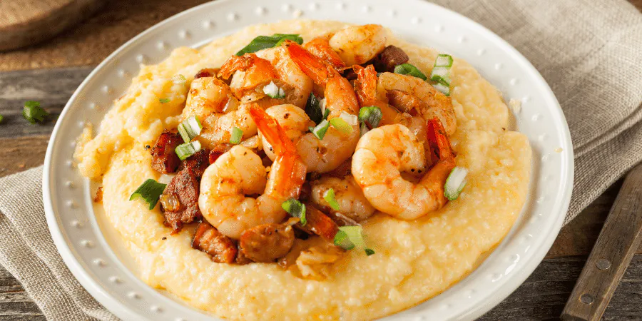 Plate of shrimp and creamy grits topped with sliced scallions