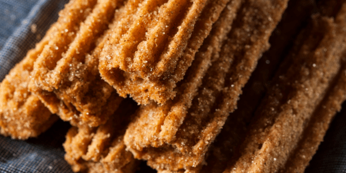 Close-up of a stack of ridged cinnamon sugar churros on a dark cloth