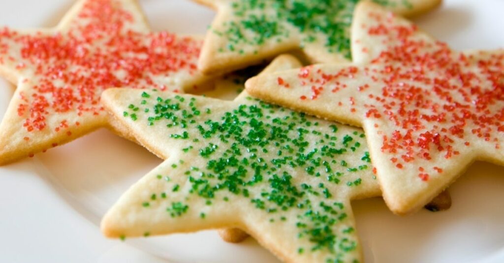 Star-shaped sugar cookies topped with red and green sanding sugar on a white plate