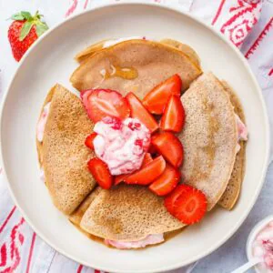 Close-up of folded crepes filled with strawberry cream and topped with sliced strawberries