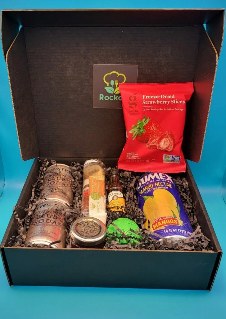 Open Rockoly happy hour kit box with mango nectar, freeze-dried strawberries, soda cans and mixers