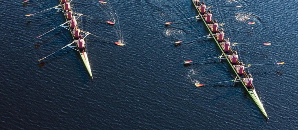 Aerial view of two rowing eights crews pulling in unison across dark blue water