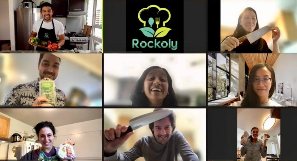 Video call grid of eight home cooks holding chef's knives and ingredients around a Rockoly logo tile