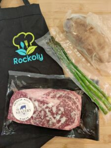 Wagyu cooking kit with a Rockoly apron, vacuum-sealed steak, asparagus and potatoes