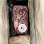 Marbled wagyu steak in vacuum-sealed packaging packed inside a cooking kit shipping box