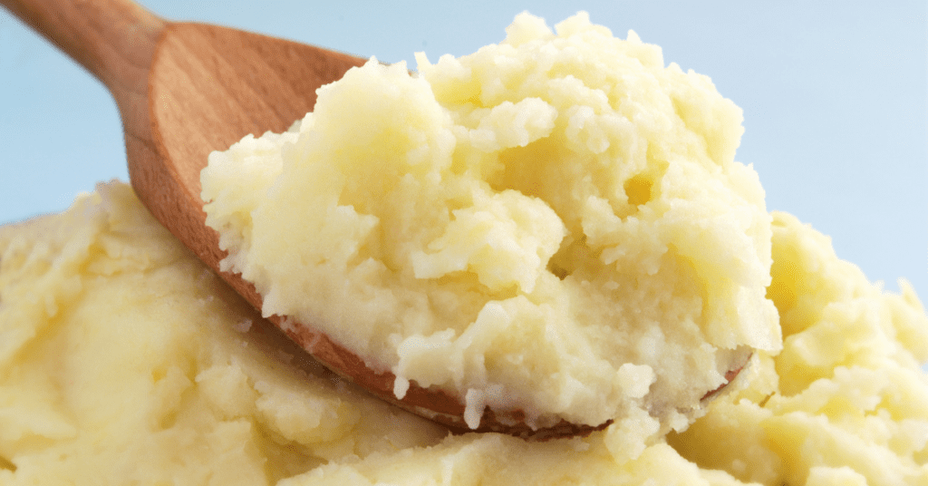 Wooden spoon lifting a scoop of creamy mashed potatoes