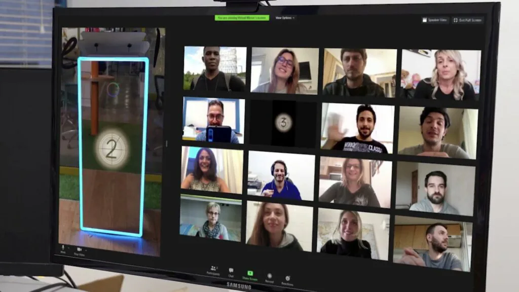 Monitor showing a video call with sixteen participants and a photo booth countdown in one tile