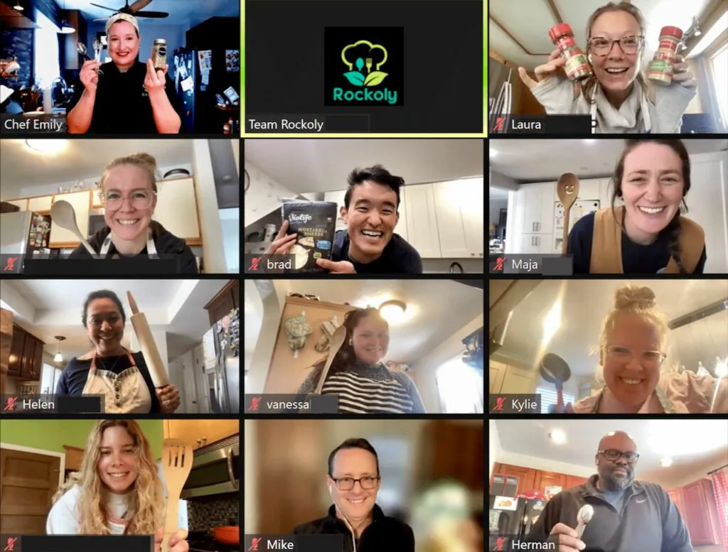 Chef Emily and her class hold up spice jars and utensils on a virtual cooking class video call