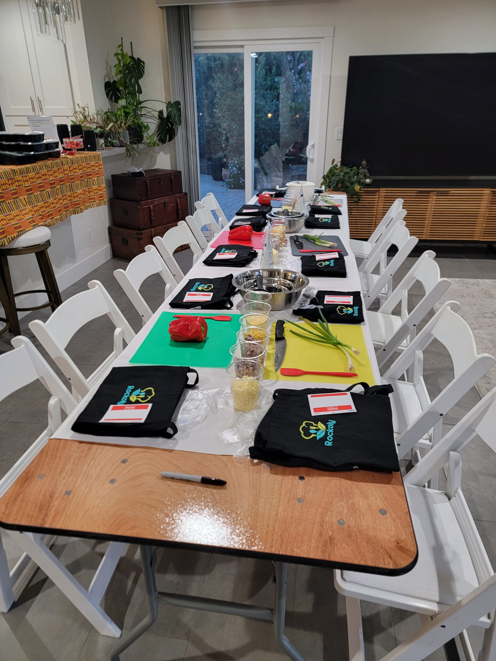 Long table set with cutting boards, prep bowls and folded aprons for an in-person cooking class