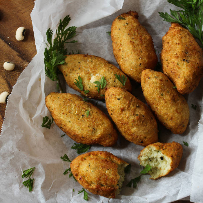 Golden fried black-eyed pea fritters on parchment with parsley and scattered dried peas