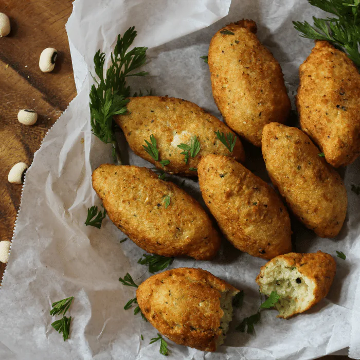 Golden fried black-eyed pea fritters on parchment with fresh parsley and dried black-eyed peas