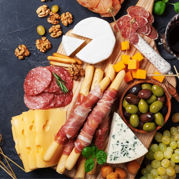 Charcuterie board with brie, blue cheese, salami, prosciutto, olives, grapes and breadsticks