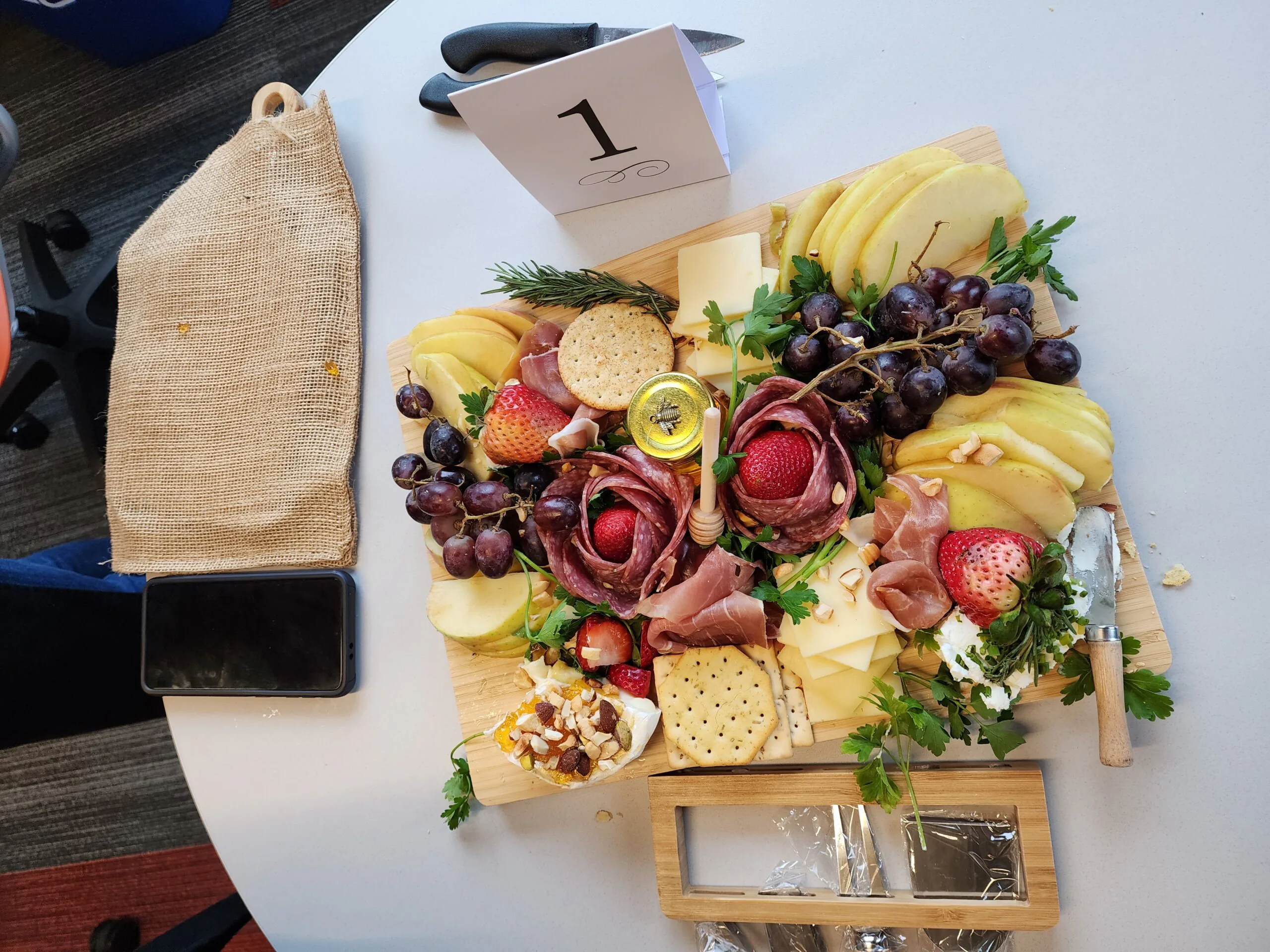 Charcuterie board of cured meats, cheeses, grapes, strawberries and crackers on a numbered event table