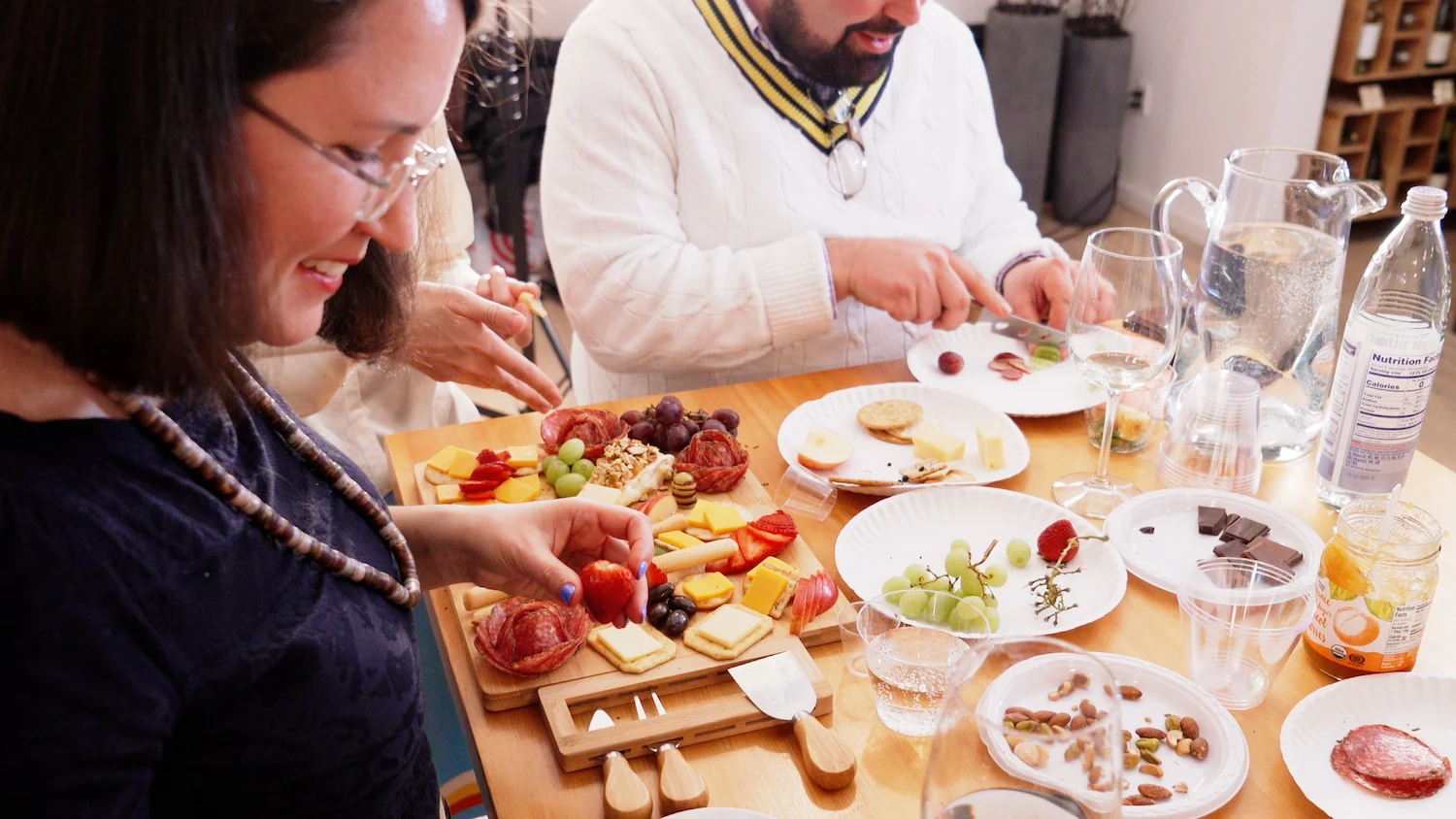 Colleagues around a table sharing a charcuterie board of cured meats, cheese and fruit