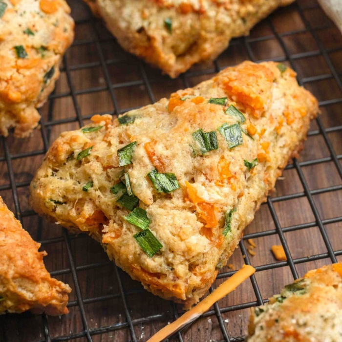Cheddar and chive scones flecked with cheese and herbs cooling on a wire rack