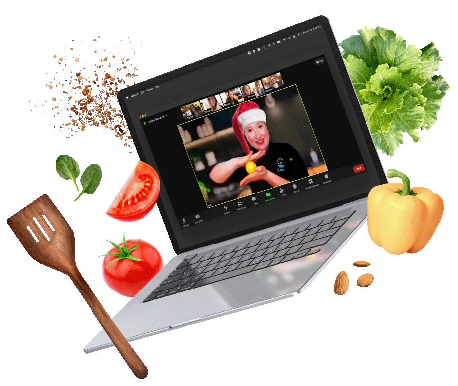 Chef Emily in a Santa hat leading a cooking class on a laptop video call, ringed by fresh vegetables