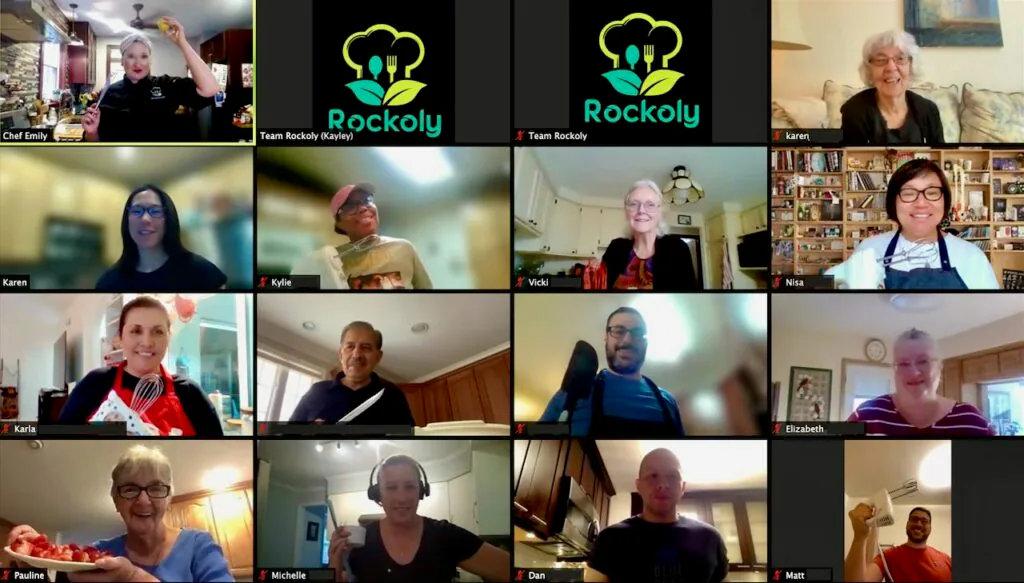 Chef Emily holding up a lemon on a video call as a dozen coworkers cook along in their kitchens