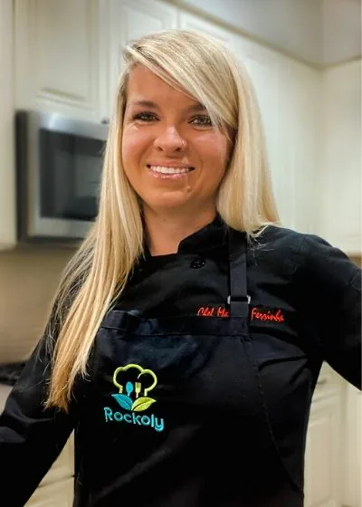 Chef Marcela in a black chef coat with her name embroidered in red, standing in a kitchen
