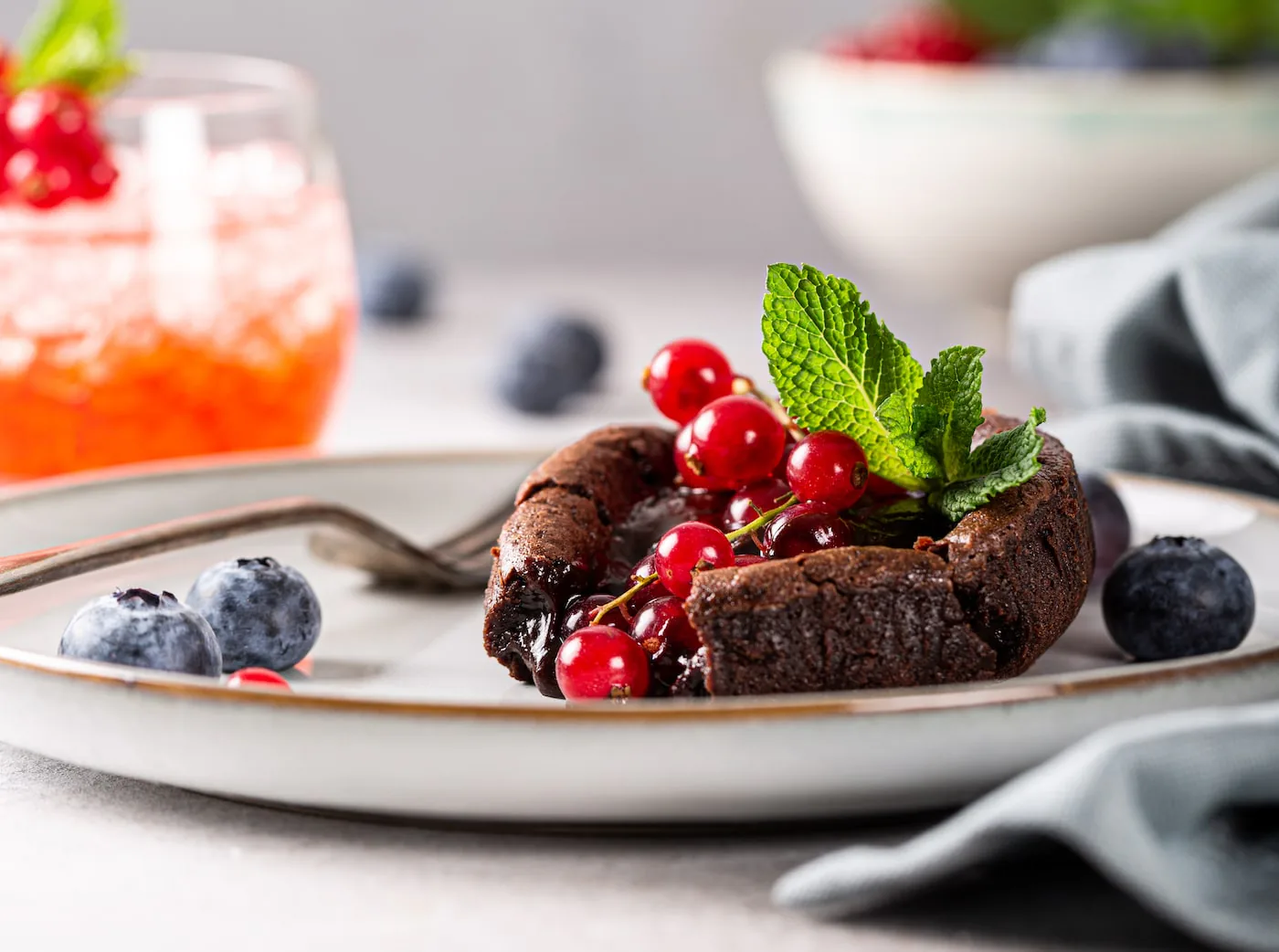 Warm chocolate lava cake topped with red currants and mint, with blueberries alongside