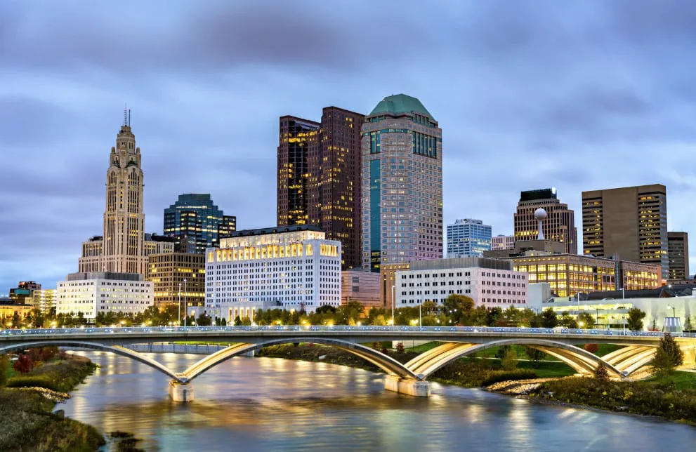 Columbus skyline lit at dusk with a bridge crossing the Scioto River