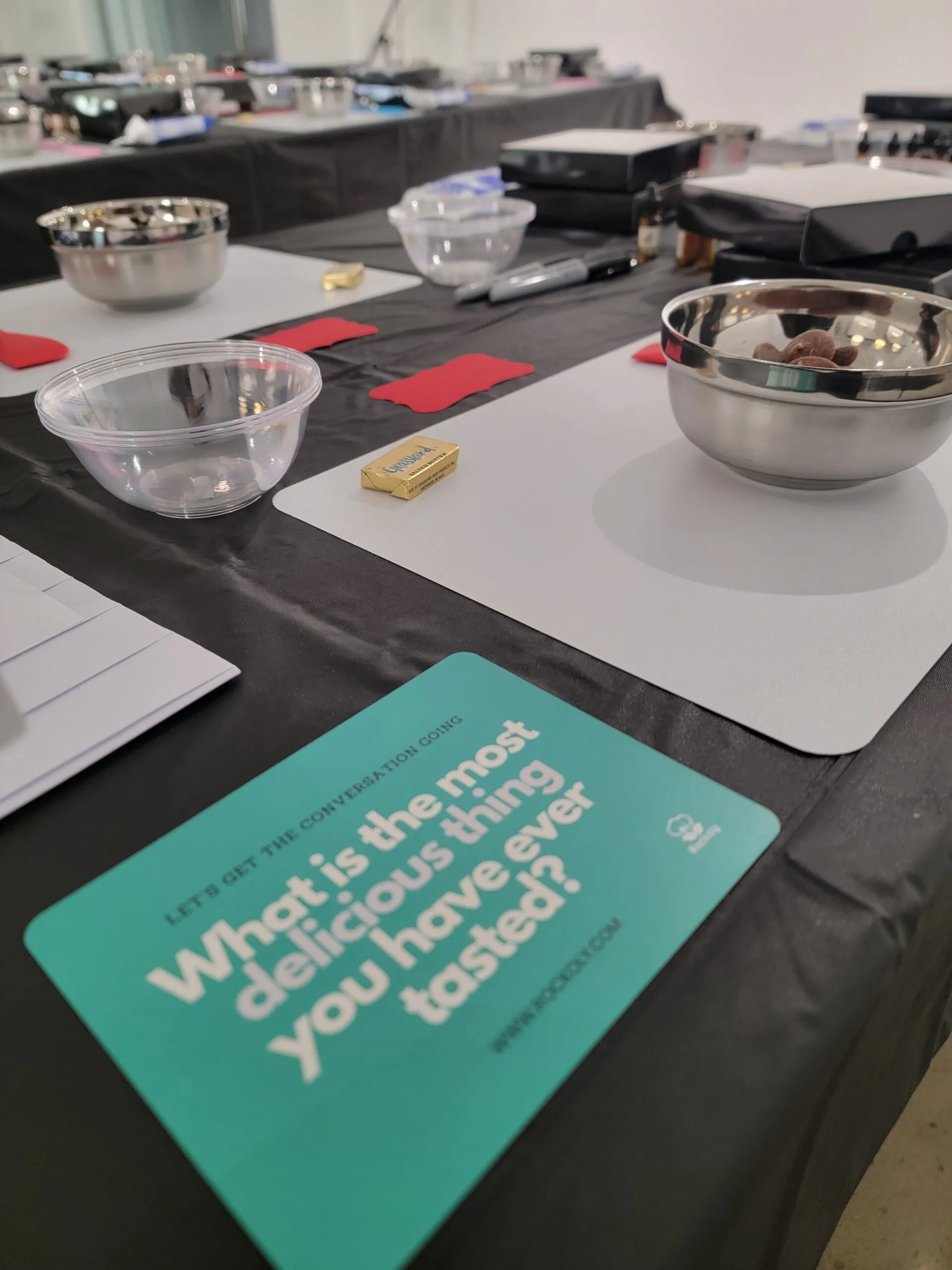 Teal card asking What is the most delicious thing you have ever tasted on a table of mixing bowls