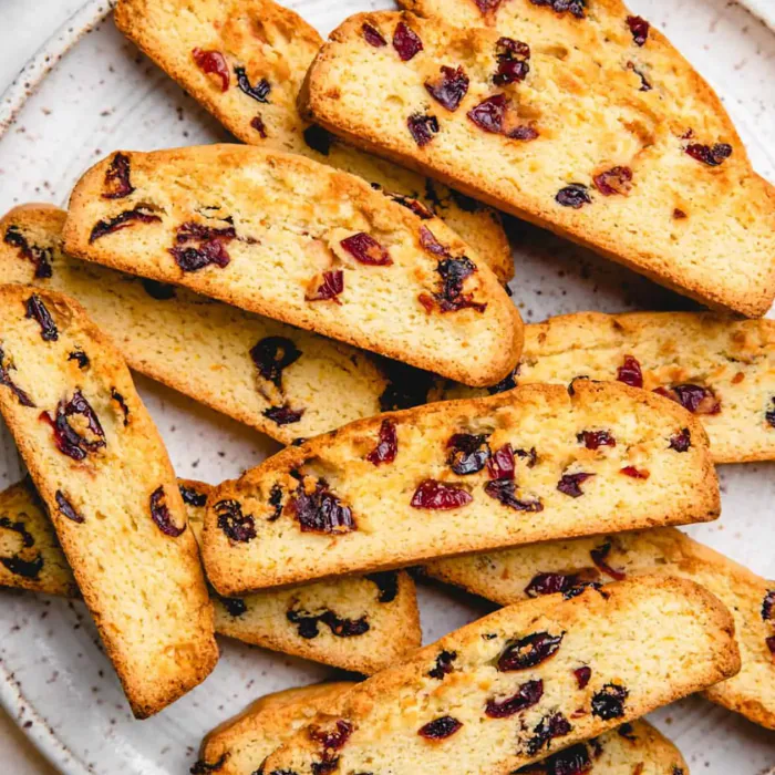 Golden biscotti slices studded with dried cranberries piled on a plate