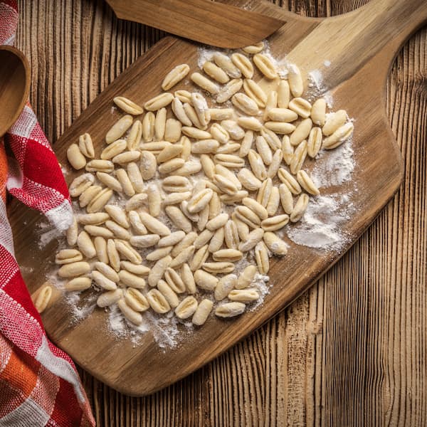 Fresh uncooked cavatelli pasta dusted with flour on a wooden board