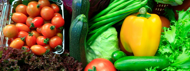 Close-up of fresh produce including cherry tomatoes, zucchini, green beans, yellow pepper and lettuce