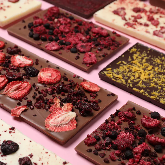 Rows of chocolate bars topped with freeze-dried strawberries, raspberries and citrus zest