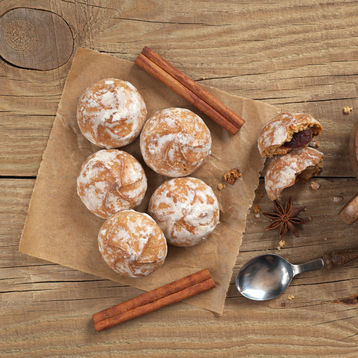 Round glazed gingerbread cakes on parchment with cinnamon sticks and star anise, one broken open