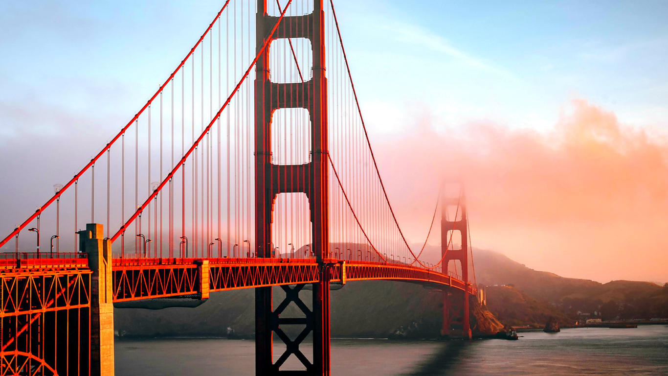 Golden Gate Bridge stretching across the bay under a pink and blue sunset sky