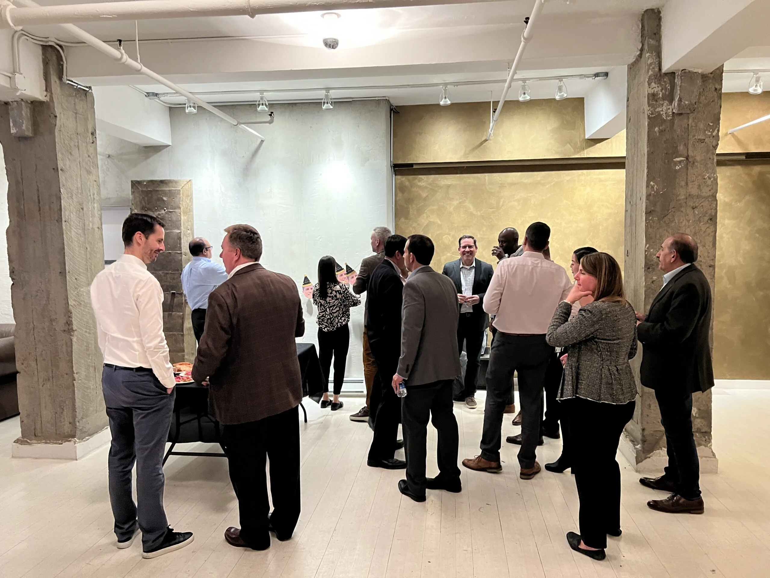 Guests in business attire mingling with drinks in a loft space with concrete columns