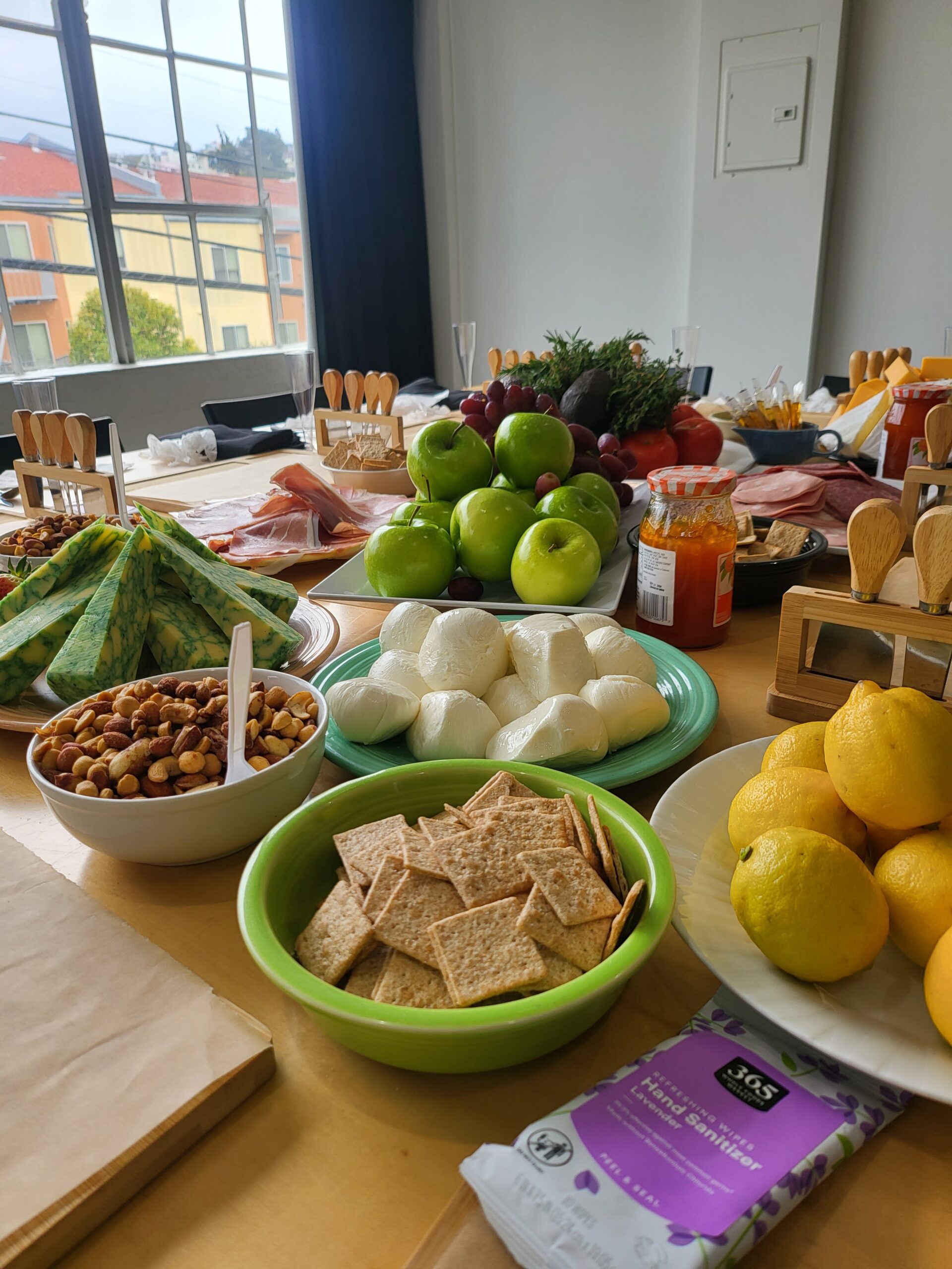 Table spread of mozzarella, crackers, olives, green apples and lemons laid out for a cooking event