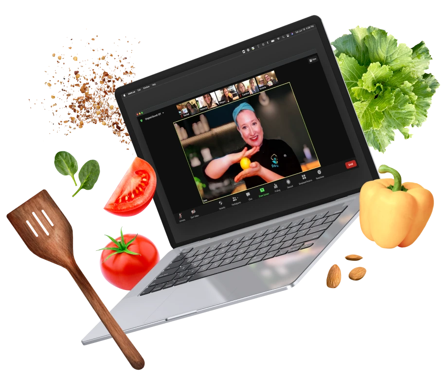 Laptop open to a video call with a smiling cook in a bandana, ringed by fresh vegetables and a spatula